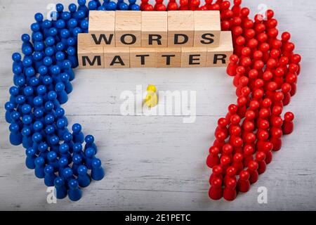 wooden blocks  in a white and grey board with the text words matter, surrounded by blue and red wooden figurines, yellow speaker in the middle Stock Photo