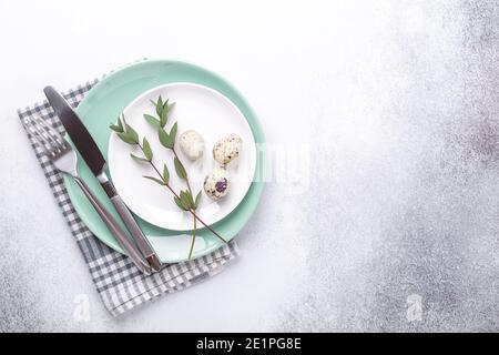 Empty mint and white plates, linen napkin, eucalyptus leaves and eggs on stone background Easter background - Image Stock Photo