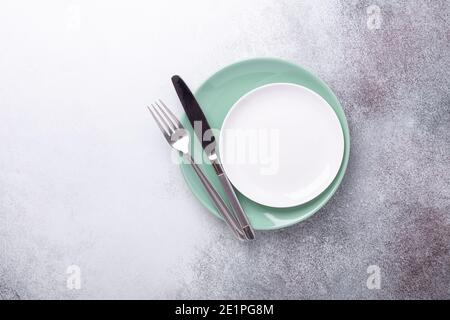 Empty mint and white plates, knife and fork on stone background Copy space Top view - Image Stock Photo