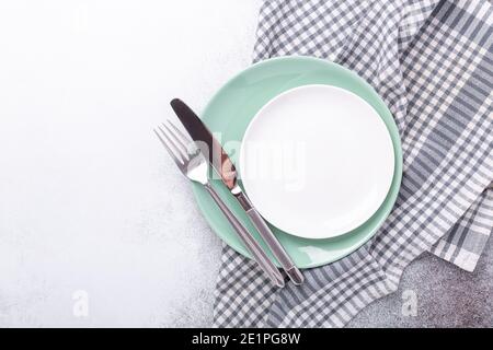 Empty mint and white plates, linen napkin, knife and fork on stone background Copy space Top view - Image Stock Photo