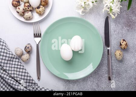 Easter table setting. Green mint plate, eggs, hyacinth and silver cutlery on stone background. Copy space. Top view - Image Stock Photo
