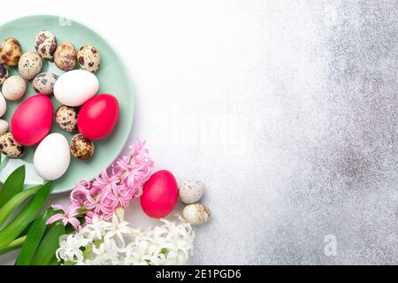 Easter composition. Green mint plate, easter eggs, pink and white hyacinth on stone background. Copy space. Top view - Image Stock Photo