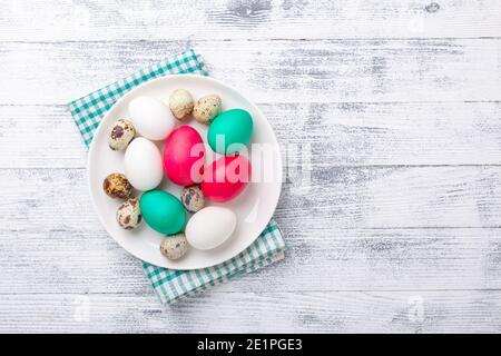 Easter eggs in white plate on wooden background. Easter concept. Top view. Copy space - Image Stock Photo