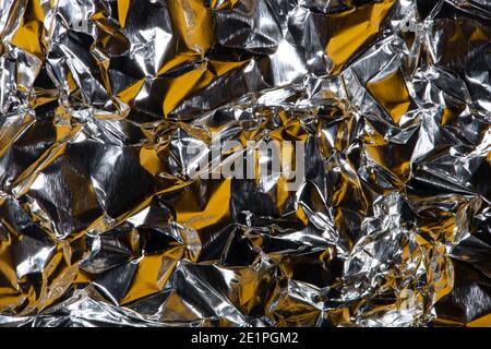 Abstract background with crumpled foil texture, silver and yellow colours. Stock Photo