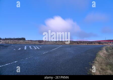 Old and well-worn stop road sign painted with white on Old Military Road in Wicklow Mountains, Co. Dublin, Ireland. Long exposure. Clouds moving Stock Photo