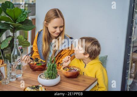 Mother and son eating Raw Organic Poke Bowl with Rice and Veggies close-up on the table. Top view from above horizontal Stock Photo