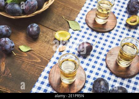 Rakija, raki or rakia is a Balkan strong alcoholic drink brandy type based on fermented fruits. Plum rakia on rustic wooden table. Stock Photo