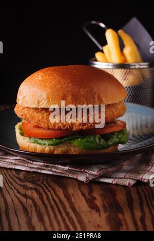 Chicken fillet in a in a brioche bun with lettuce tomatoes and fries shot with creative lighting