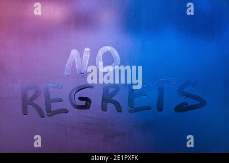 words no regrets hand written on purple-blue night foggy window glass Stock Photo