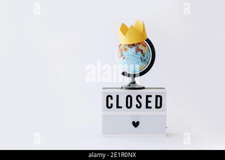 Concept of lock down, Covid 19. Text on display in lightbox and globe with crown on it, light background. Stock Photo
