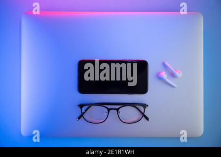 On a colored background, Laptop, glasses, pen, headphones, top view. Business concept Stock Photo