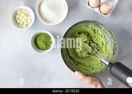female hands mixing dough with mixer in bowl Stock Photo