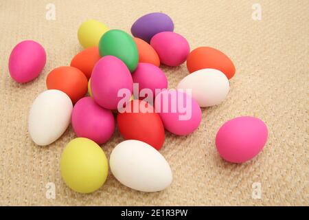 Multi colored easter eggs against a natural beige woven matt background. Stock Photo
