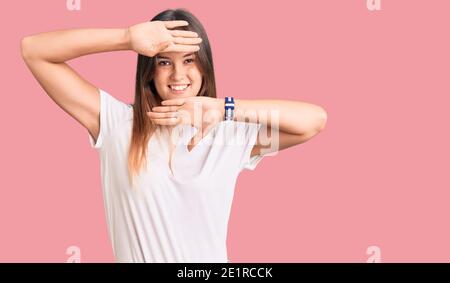 Beautiful caucasian woman wearing casual white tshirt smiling cheerful playing peek a boo with hands showing face. surprised and exited Stock Photo