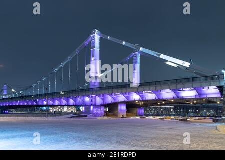 The bridge is lit with neon lights on a winter evening. Stock Photo