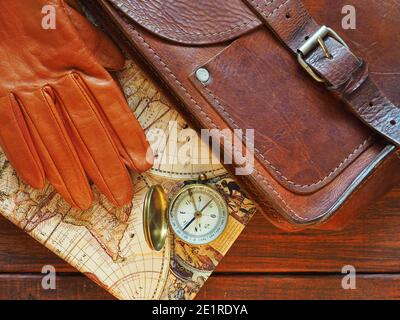 Travel planning. Old compass, map, leahter briefcase and gloves on wooden background. Stock Photo