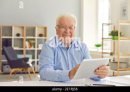 Happy senior man shopping online, managing budget and reading news using tablet. Stock Photo