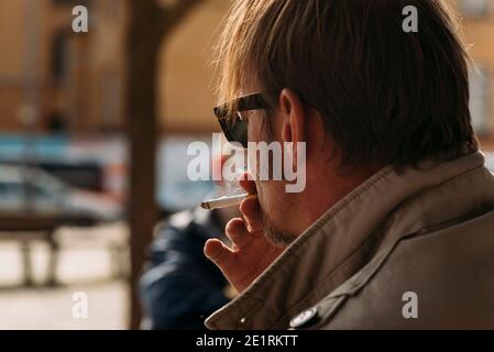 husband smokes cigarettes behind my back A smoking man from behind, portrait of a smoking man from behind, smoke, cigarette Stock Photo My husband is sneaking cigs