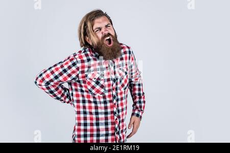 brutal bearded man wear checkered shirt having lush beard and moustache feel pain in back, medicine. Stock Photo