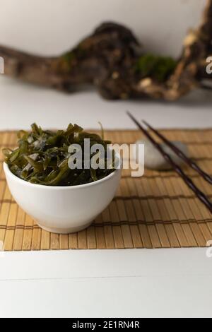 Edible seaweed in a white bowl on a bamboo rug. Oriental food concept. Healthy eating. Stock Photo