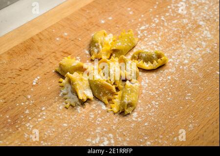 Ravioli del plin, typical pasta from Langhe, Piedmont, Italy - freshly made raw agnolotti on wooden cutting board Stock Photo