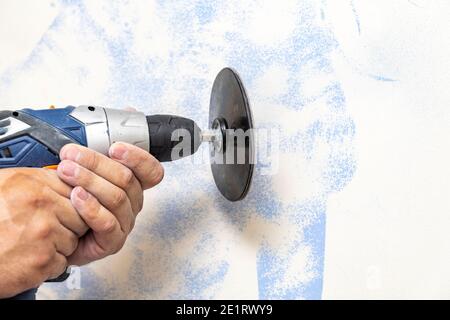 The plasterer levels the surface of the wall with a sander. the master removes the old paint from the surface. Copy space. Stock Photo