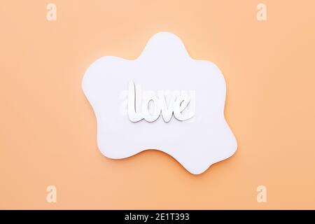 Wooden word Love on white concrete geometric shape on orange background, top view Stock Photo