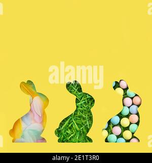 A silhouette of a rabbit is cut out of paper. Background of green grass. Happy Easter greeting card in trendy colors. Yellow and gray are the colors o Stock Photo