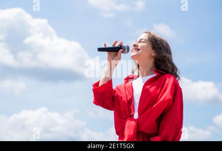 Cute and stylish. having a party. Happy kid with microphone. Singing Songs in karaoke. Lifestyle and People Concept. make your voice louder. Music and life. teen girl singing song with microphone. Stock Photo