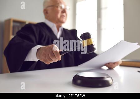 Judge holding gavel, hitting sound block and pronouncing sentence in court of law Stock Photo