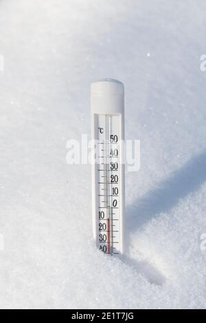 A thermometer in a snowdrift in winter shows a low temperature. Weather concept. Stock Photo