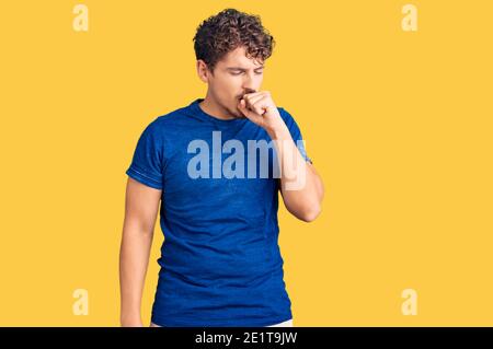 Young handsome man with curly hair wearing casual clothes feeling unwell and coughing as symptom for cold or bronchitis. health care concept. Stock Photo