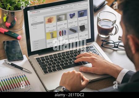 Online shop website developer, Man working with a computer laptop, eshop web page on the screen, office desk background. Stock Photo