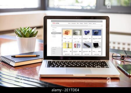 Online shop website, Eshop, ecommerce, digital marketing web page on a laptop screen, office desk background. Stock Photo