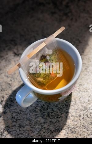 A filter bag with wooden stick filled with herbal tea inside a cup Stock Photo