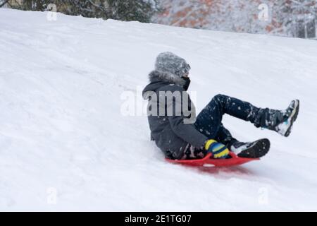Boy enjoying a sleigh ride. Kid playing outdoors in snow Stock Photo