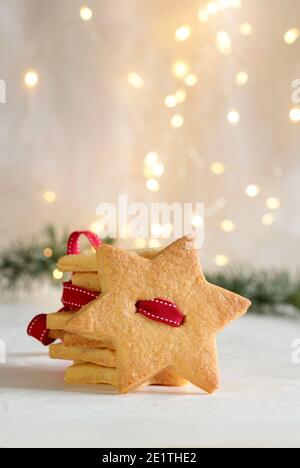 Christmas cookie in the shape of star. Blurred Christmas lights background. Stock Photo