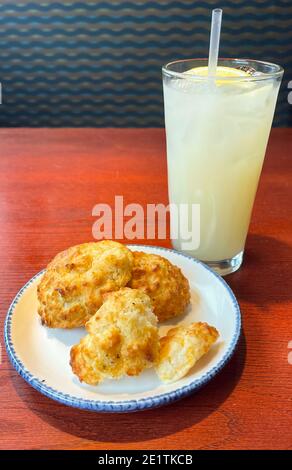 Three Cheddar Biscuits on a Plate with a Glass of Ice Cold Lemonade at a Sea Food Restaurant Stock Photo