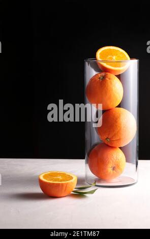 Fresh oranges in a glass vase. Dark background. Copy space. Stock Photo