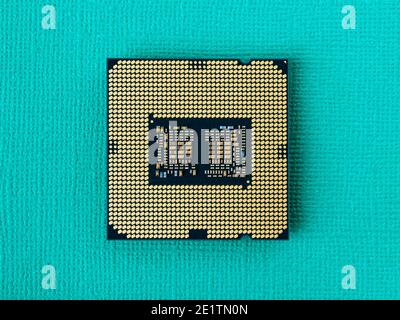 Pc micro CPU with gold plated contacts on a textured turquoise background. Modern central processing unit close-up. Desktop computer hardware macro. Stock Photo