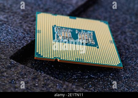 Pc micro CPU with gold plated contacts on a textured dark background. Modern central processing unit close-up. Desktop computer hardware macro. Stock Photo