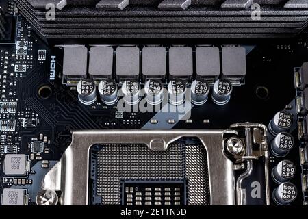 Inductors and capacitors for cpu socket powering on a modern black motherboard. Computer mainboard circuit components. Desktop hardware macro. Stock Photo