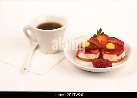 white cup expresso of coffee with strawberries and purple flowers on a table ready for breakfast italian pastries Stock Photo