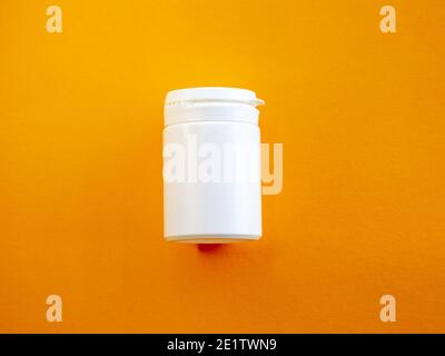 Bright yellow pillbox with medicines on a orange background. First aid kit for travel. Medicines are always with you. Stock Photo