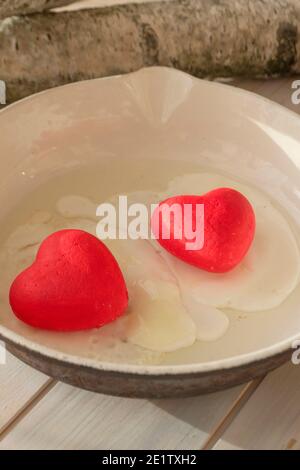 cooked egg with red hearts in a fryer, concept of belarusian revolution, vertical image Stock Photo