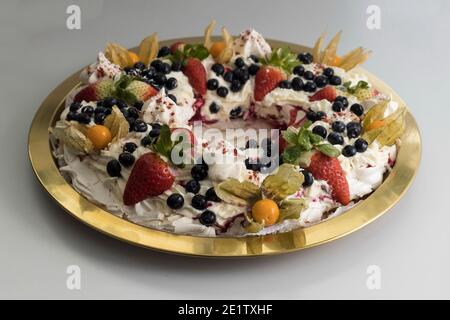 Delicious pavlova cake wreath of french meringue and whipped cream, decorated with strawberry, blueberries and physalis, view from above Stock Photo