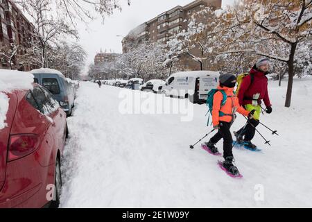 Two people walking in the middle of the street with snow rackets, 2021 (Madrid, Spain). Stock Photo