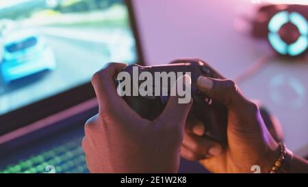 Close up of black man hands holding joystick and playing video game on the laptop. High quality photo Stock Photo