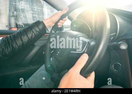 Man driving car on a sunny day. Close up of driver hands on the steering wheel Stock Photo