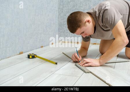 Young repairman is markup a wooden panel with a pencil and ruler before cutting Stock Photo